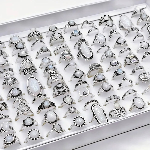 A collection of silver and white stone charm rings for women displayed in a white box.