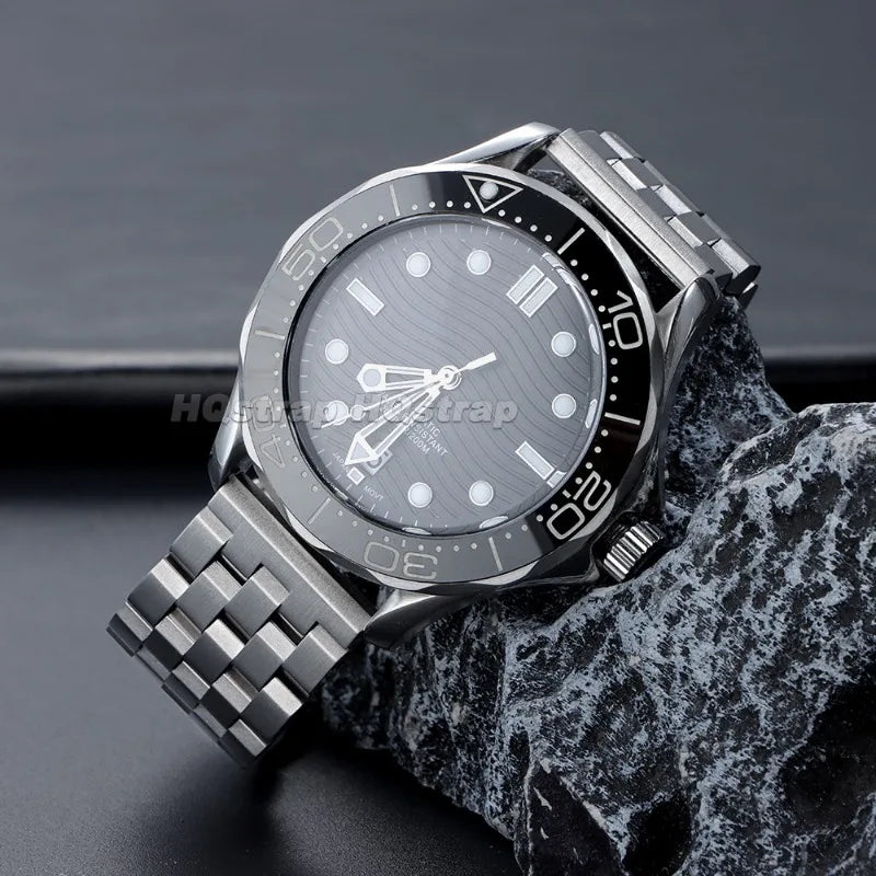 A silver stainless steel watch with a black dial and bezel is displayed on a dark surface.