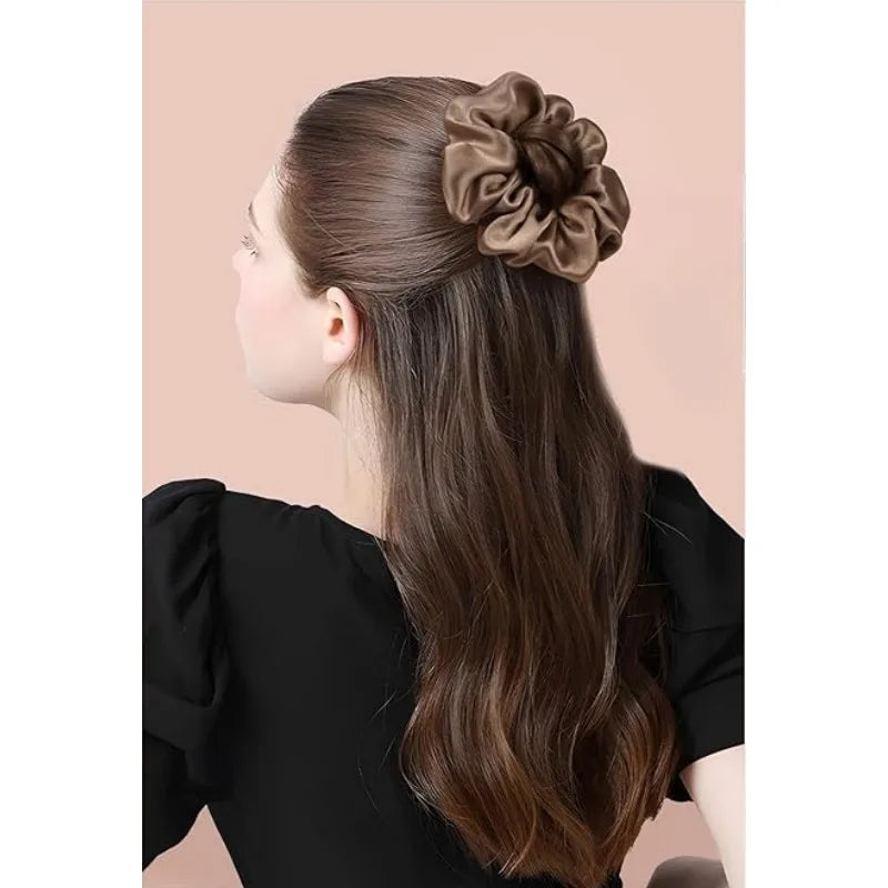 A woman shows off long brown hair styled with a large, elegant silk scrunchie hair tie.