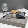 A pair of black-framed photochromic anti-blue light reading glasses resting on a gray leather case.