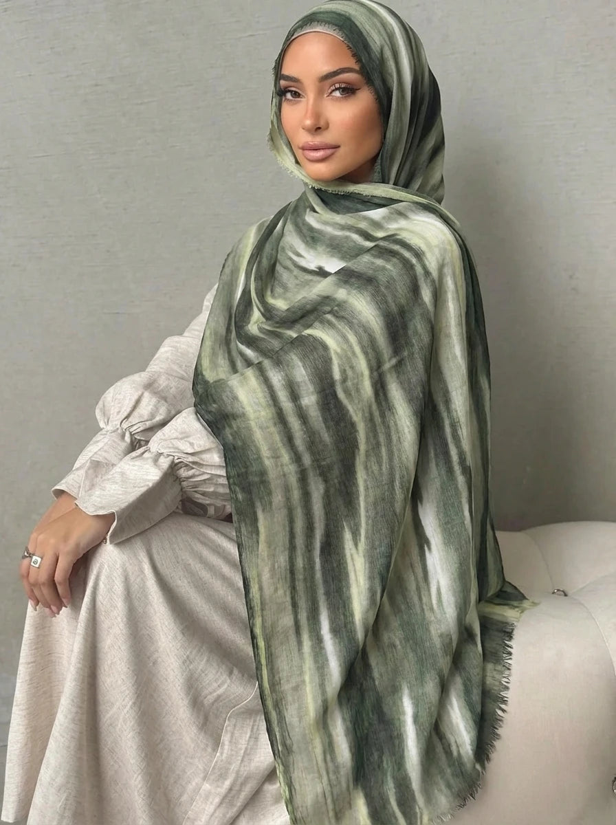 Una mujer vistiendo un elegante pañuelo de hijab a rayas verdes y blancas con un top transparente.