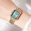 A gold-toned rhinestone quartz wristwatch with a light blue face and gold links on a woman's wrist.