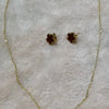 Collar de planta de acero inoxidable chapado en oro con pendientes a juego, exhibido sobre un fondo peludo
