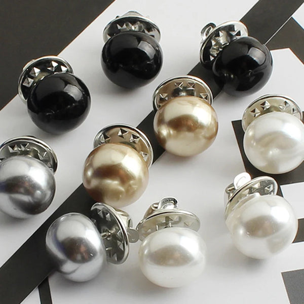 Une collection de boutons de perles argentées et noires sur un fond blanc.