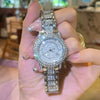 A hand holds an elegant rhinestone quartz fashion watch with a silver band and crystal face.