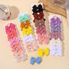 A collection of handmade ribbon bow hair clips in various colors and shades displayed on white cards.