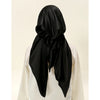 A black satin silk hijab is draped and styled on a white garment.