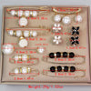 A set of adjustable pearl brooches and jewelry displayed on a light beige box.
