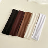 Five solid colored fabric headbands in black, brown, tan, cream, and white laid out on a light surface.