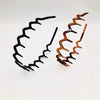 A set of black and copper anti-slip toothed hair accessories arranged in a wavy line.