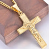A gold-colored retro Christian cross amulet necklace resting on a dark wooden surface.