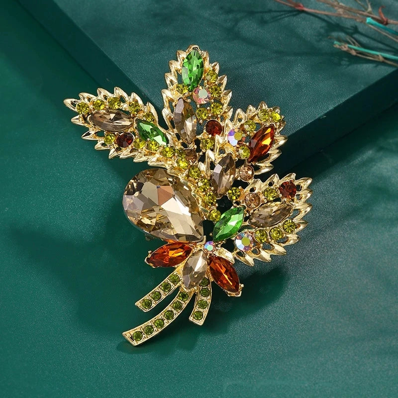 Broche florale en cristal élégante avec métal doré et pierres de couleurs variées (vert, ambre, rubis).
