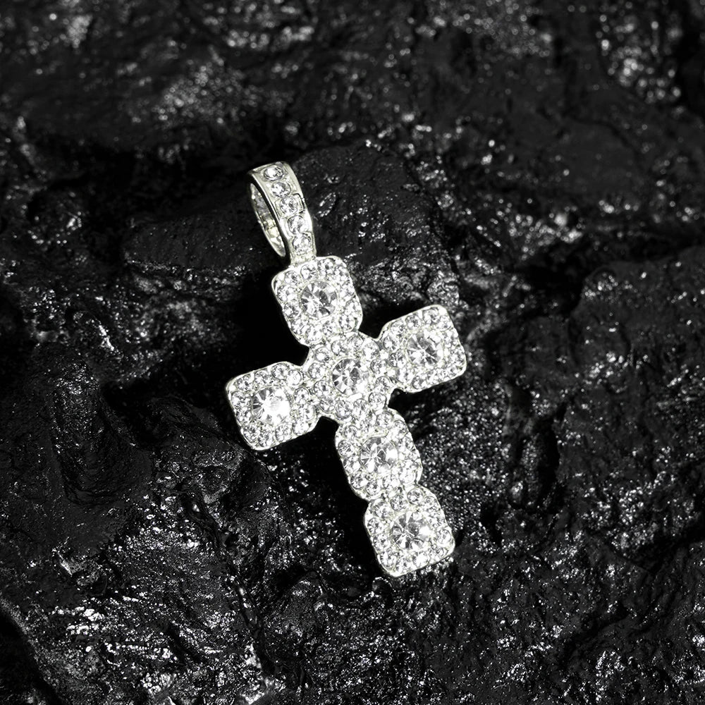 A sparkling rhinestone cross pendant necklace resting on a dark, textured surface.