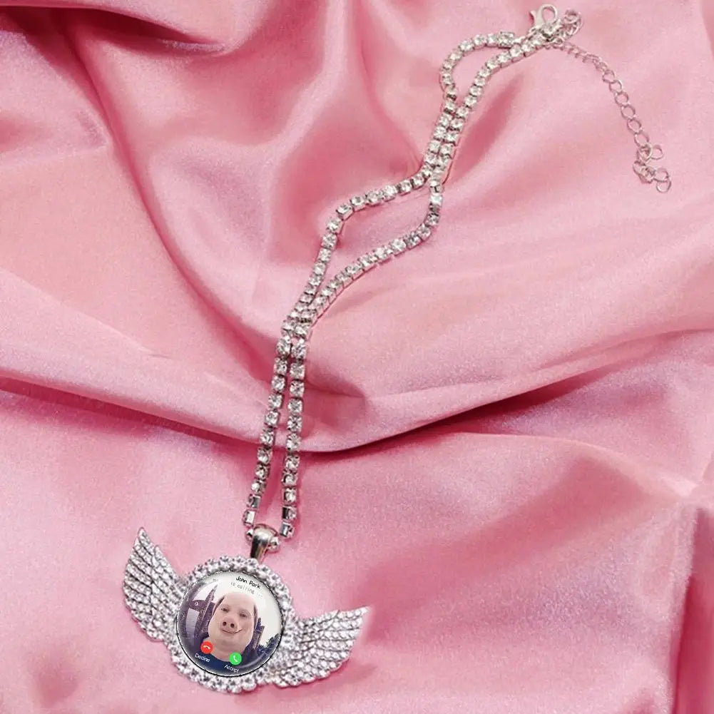 Colgante de cadena plateado con dije de alas de ángel y una foto de un bebé.