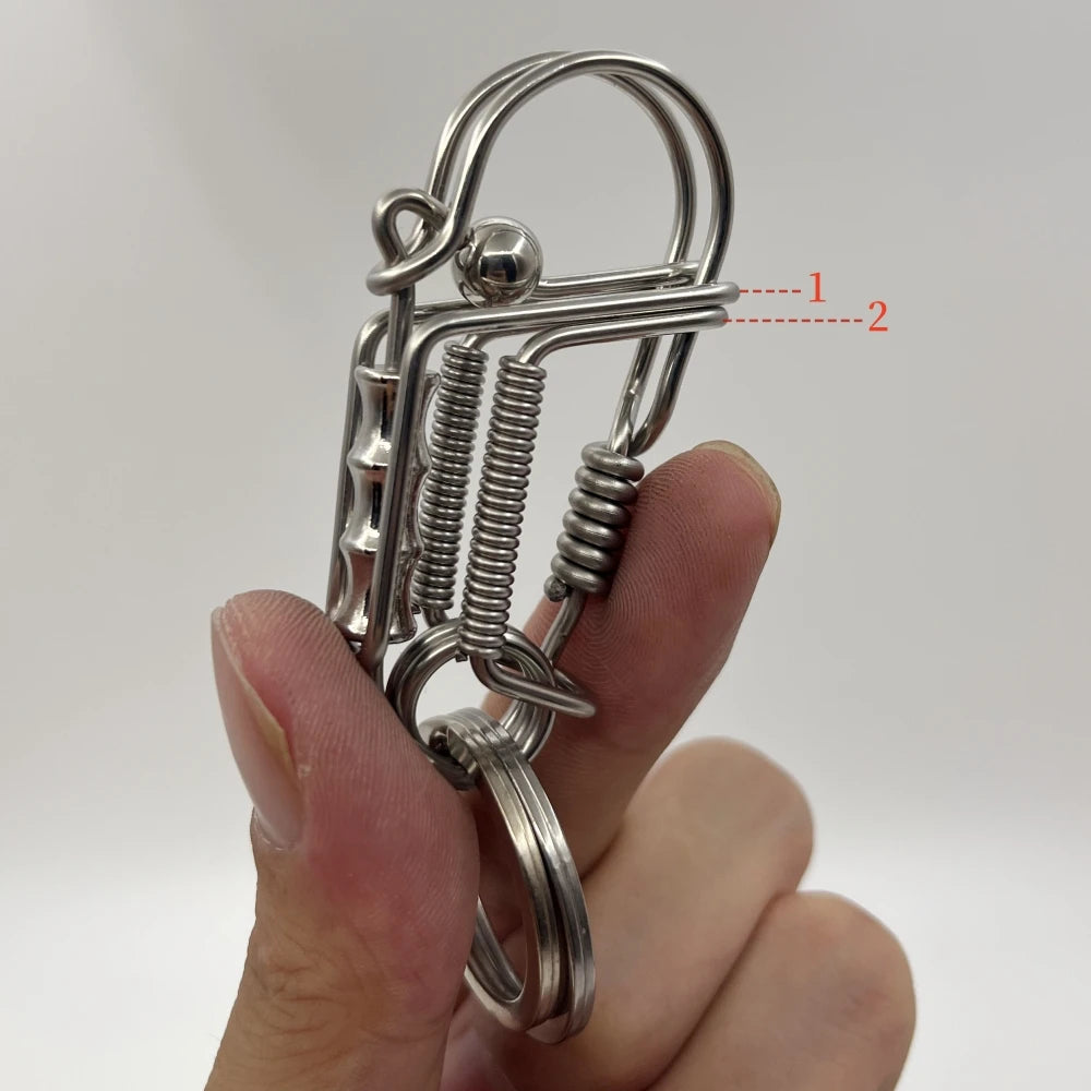 Un porte-clés mécanique en acier inoxydable avec mécanisme à ressort tenu dans une main.