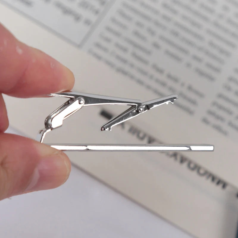A silver men's business tie clip with a copper bar clasp is held by a hand against a blurred document.