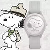 Silberuhr mit hellem grauem Armband und runder Zifferblatt neben einer Karikatur von Snoopy mit Hut