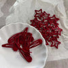 A set of red star snap clips for hair and barrettes displayed on a white plate.
