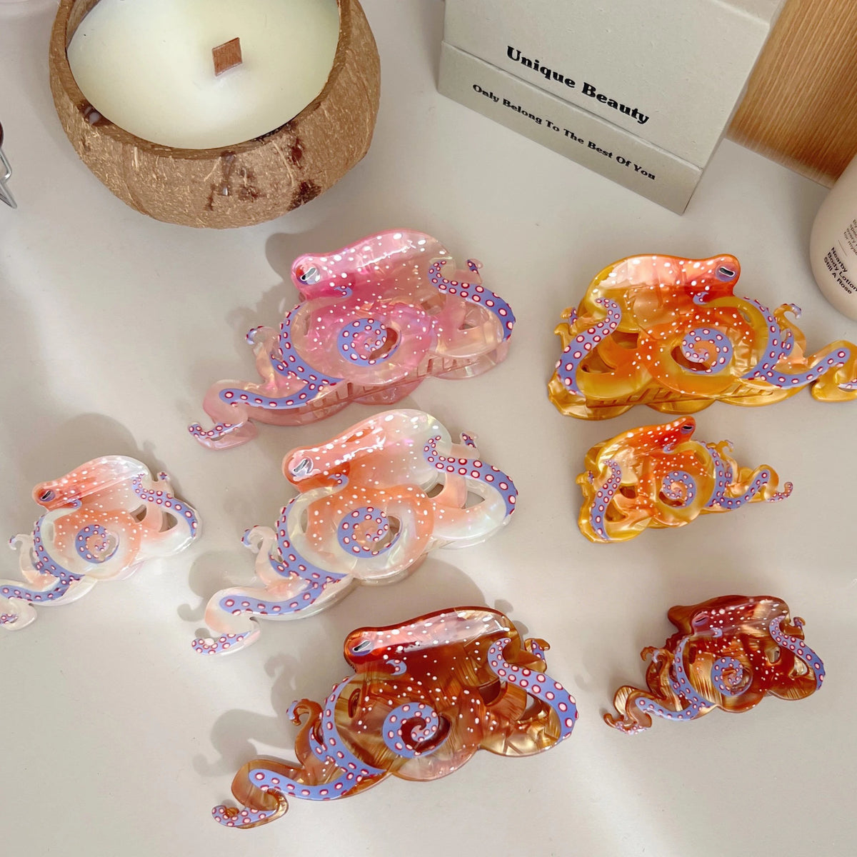 Collection de pinces à cheveux en forme d'octopus colorées, rose, violet et orange, sur une surface blanche.