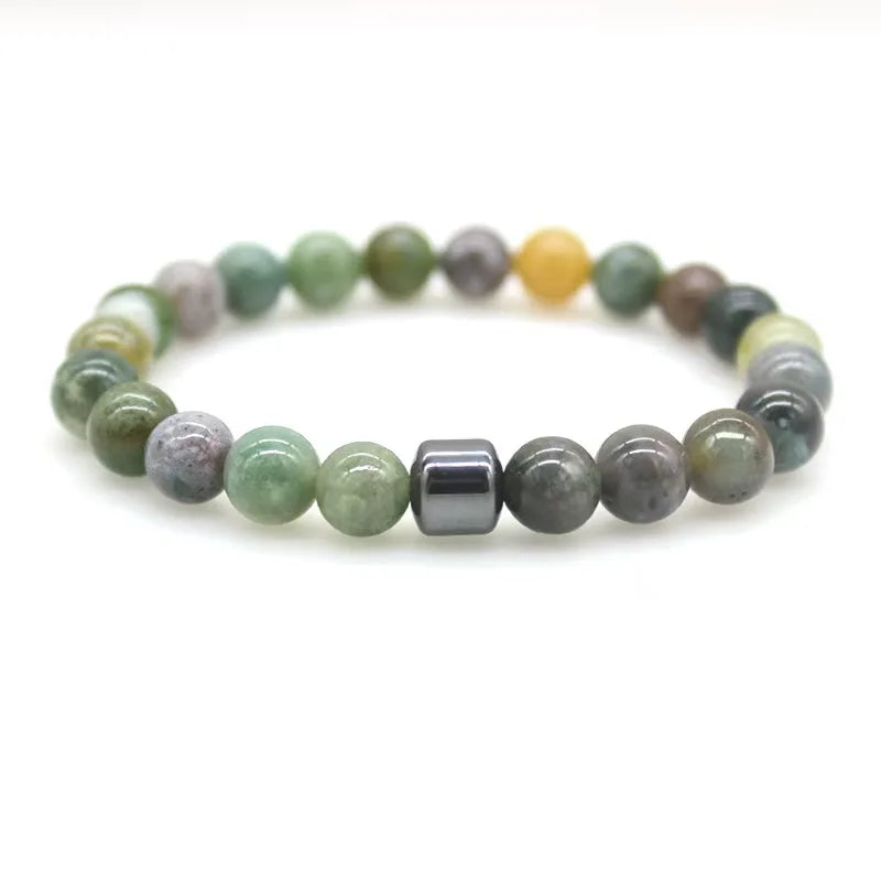 A bracelet made of polished, tumbled stones in shades of green, yellow, and gray, featuring a silver-colored bar.