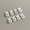 A collection of white, heart-shaped earring lifters for studs jewelry making arranged on a neutral gray surface.