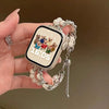 A hand holds a smartwatch with a beaded watch strap and a charm featuring cartoon animals.