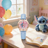 A pink and blue quartz wristwatch featuring a Stitch character design on the dial, resting on a wooden table.