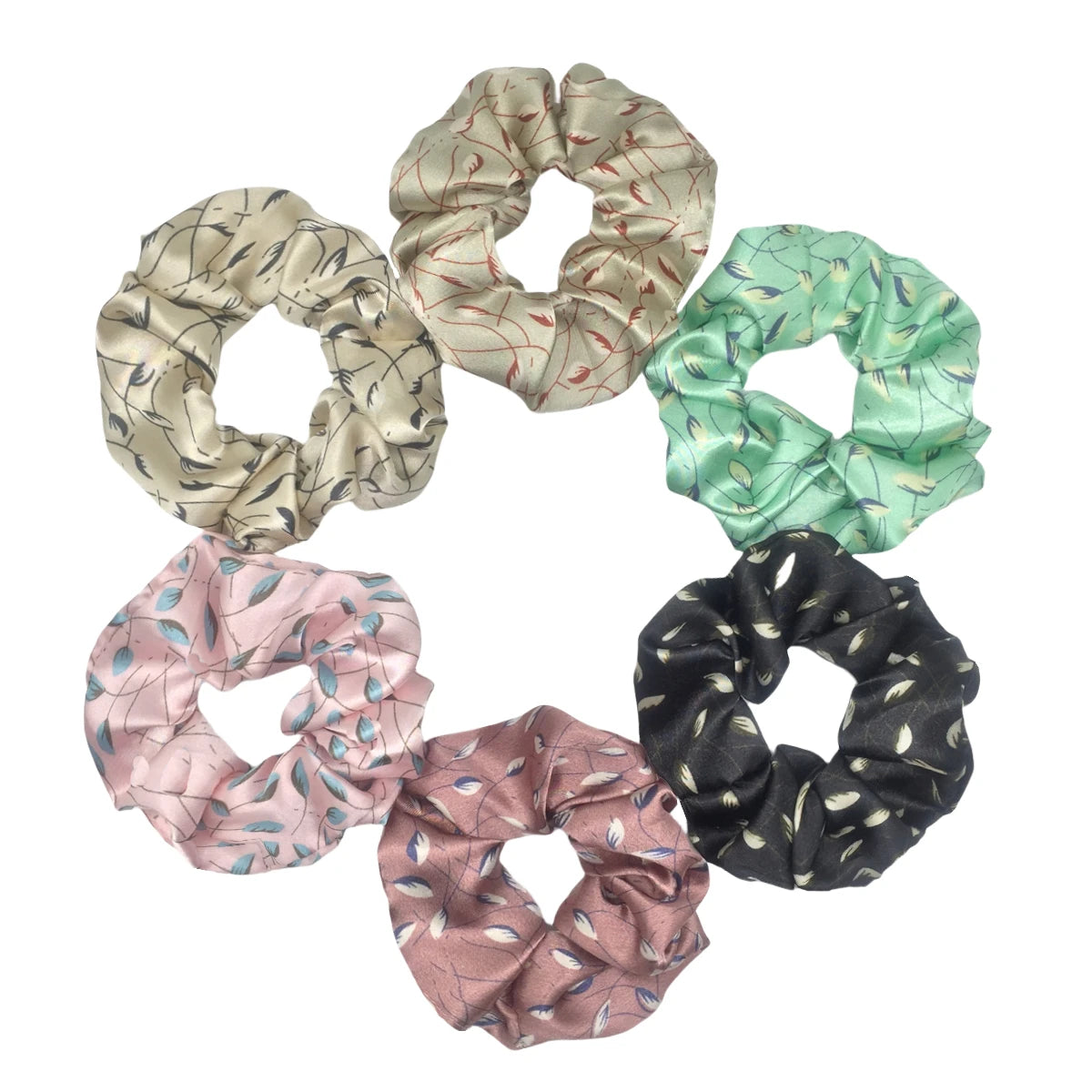 Un set de seis gomas de tela con estampado floral de satén en varios tonos de verde, beige y negro.