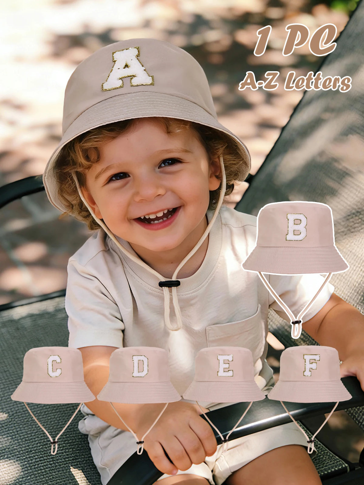 A smiling toddler wearing a beige sun hat with an A letter, surrounded by other letter hats.