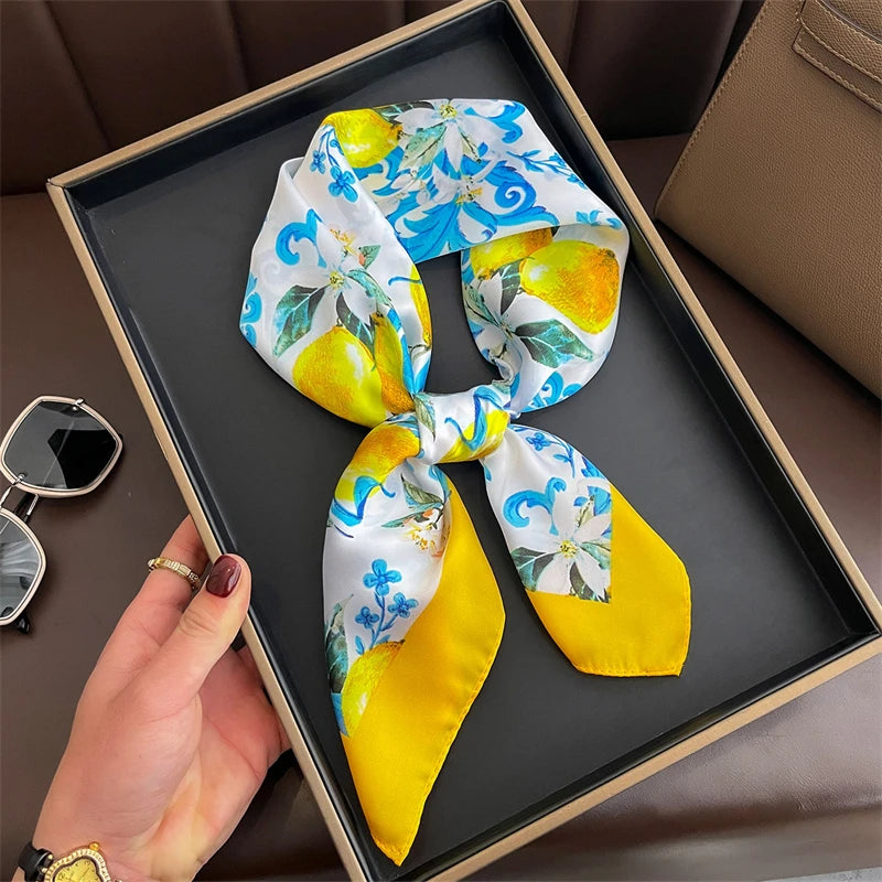 A yellow and blue floral silk scarf tied in a bow displayed in a square wooden frame.