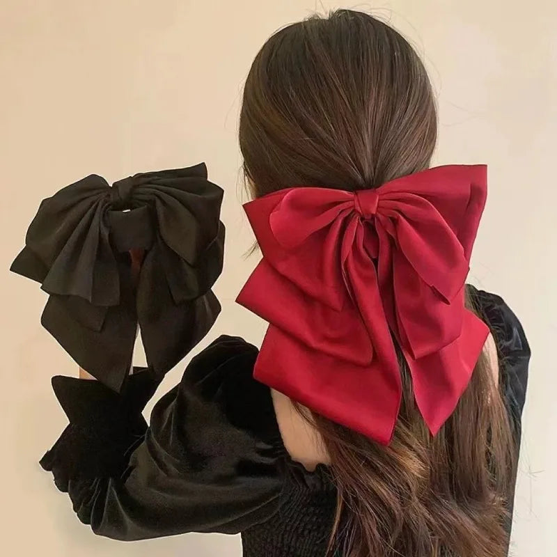 A woman shows off a large red satin bow hair clip tied in her hair.