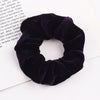 A dark purple velvet scrunchie is shown against a white background.