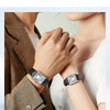 Nahaufnahme einer Frau mit einer silber-schwarzen Quarzuhr mit Lederarmband am Handgelenk.
