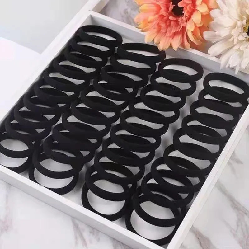 A box filled with black seamless hair ties for ponytail holders and a flower.