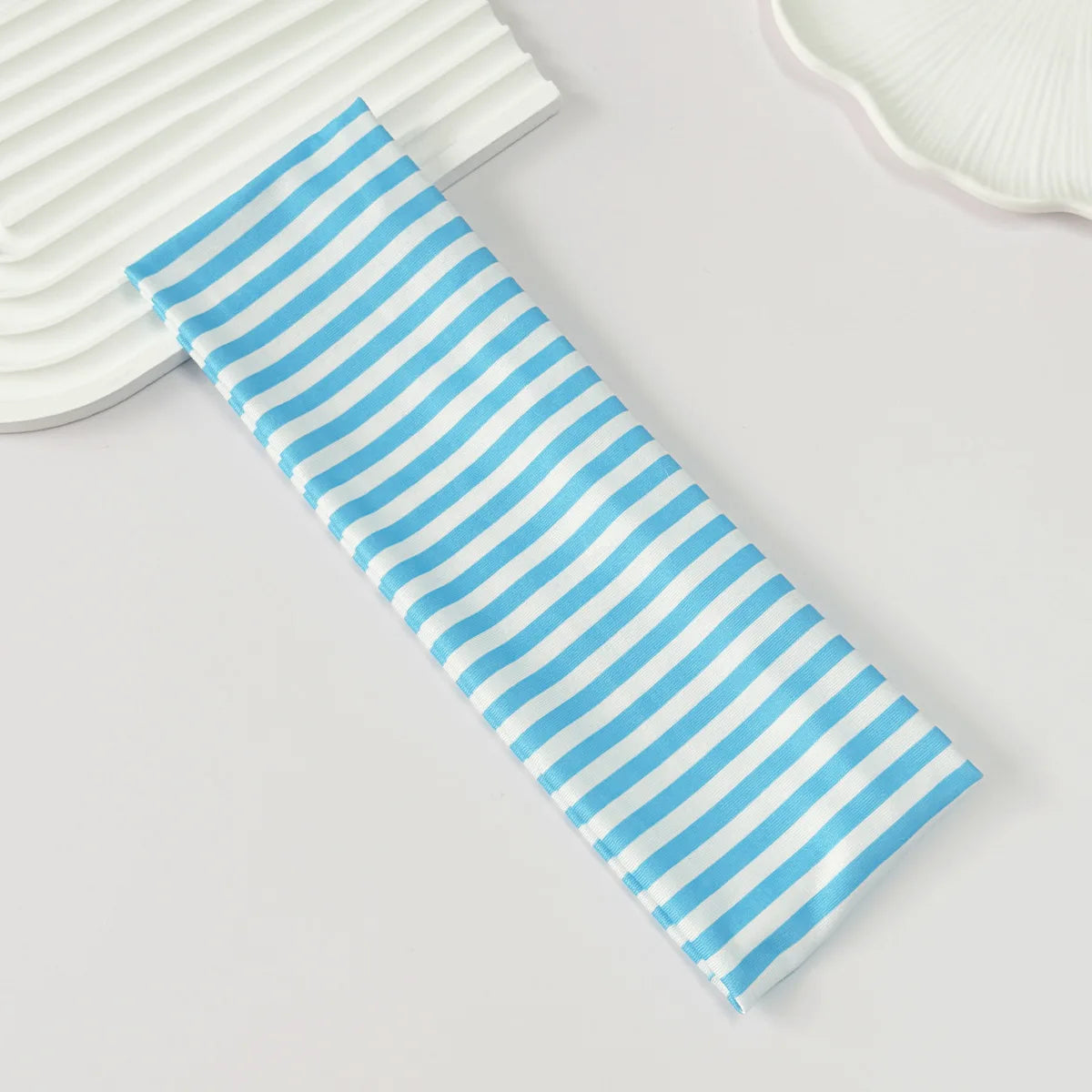 Gros plan d'un élastique pour cheveux rayé bleu et blanc sur une surface claire.