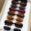 A display of various trendy leopard cat eye sunglasses arranged in a vertical line on a white tray.