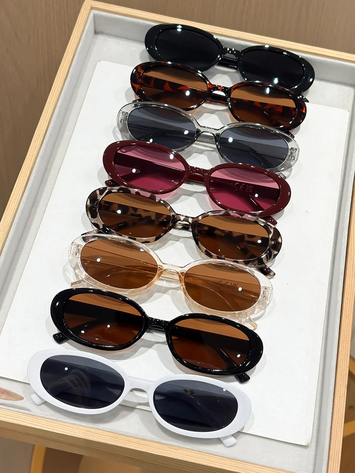 A display of various trendy leopard cat eye sunglasses arranged in a vertical line on a white tray.