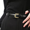 A close-up of a black PU fashion belt with a gold buckle worn on a black suit jacket.