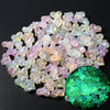 A pile of iridescent, glow-in-the-dark acrylic beads in pink and green shades.