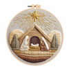 A circular embroidery kit featuring a scene of a nativity with golden rays and wooden elements.