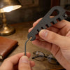 A hand holds a black precision tool used to adjust or remove eyeglasses.