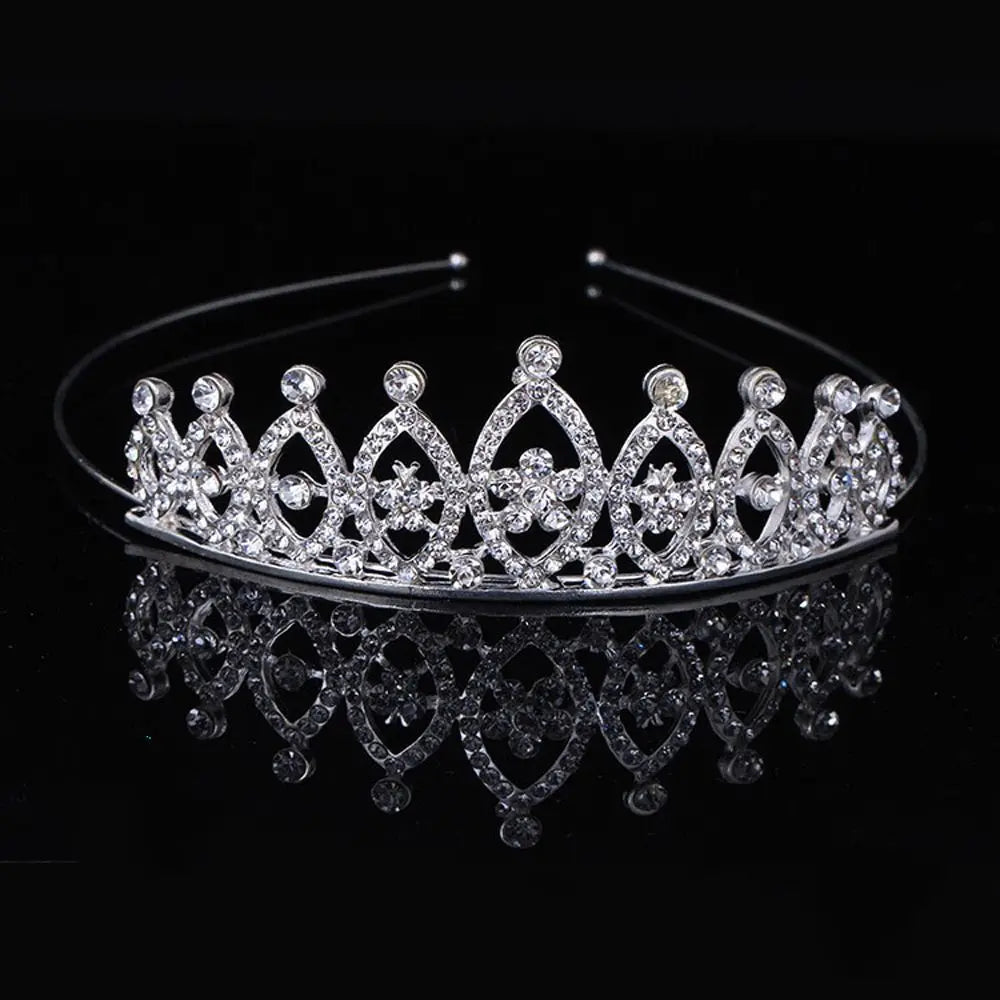 A sparkling crystal hair crown for women displayed on a dark reflective surface.