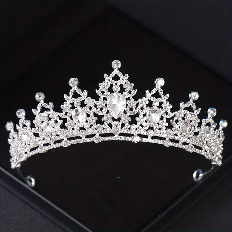 A sparkling silver crystal bridal crown with intricate detailing and a central diamond-shaped gemstone.
