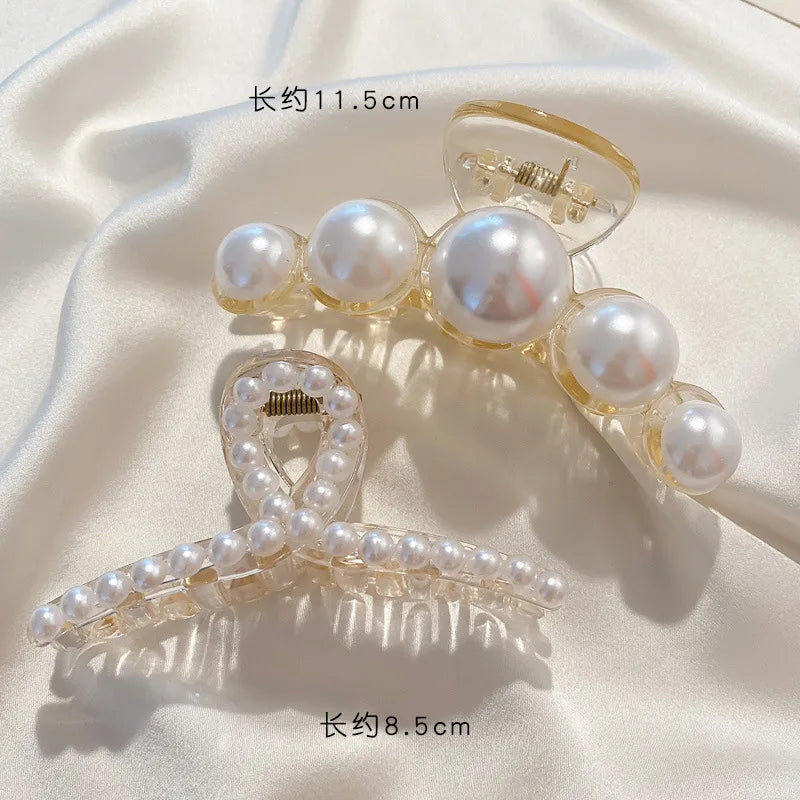 Clear simulated pearl hair claws displayed on a white satin background.
