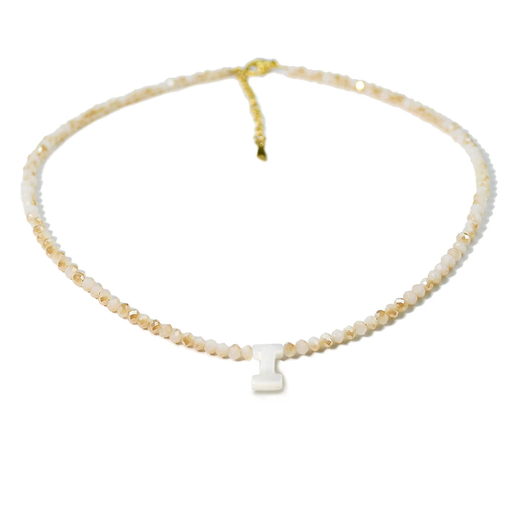 A delicate necklace made of mother of pearl beads with crystal accents and a small charm.