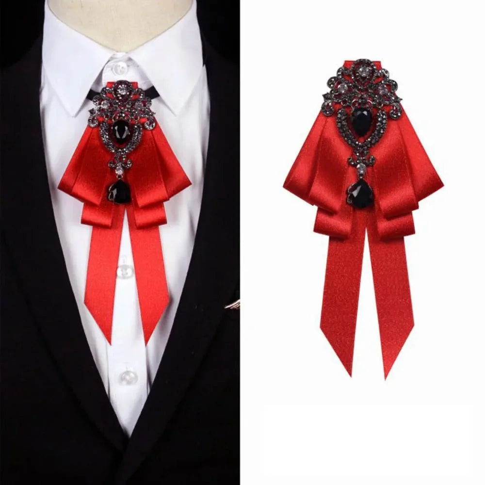 A red satin bow tie with black rhinestone embellishments worn on a white shirt collar.