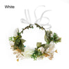 White bohemian flower headband featuring greenery and white flowers with a sheer ribbon bow.