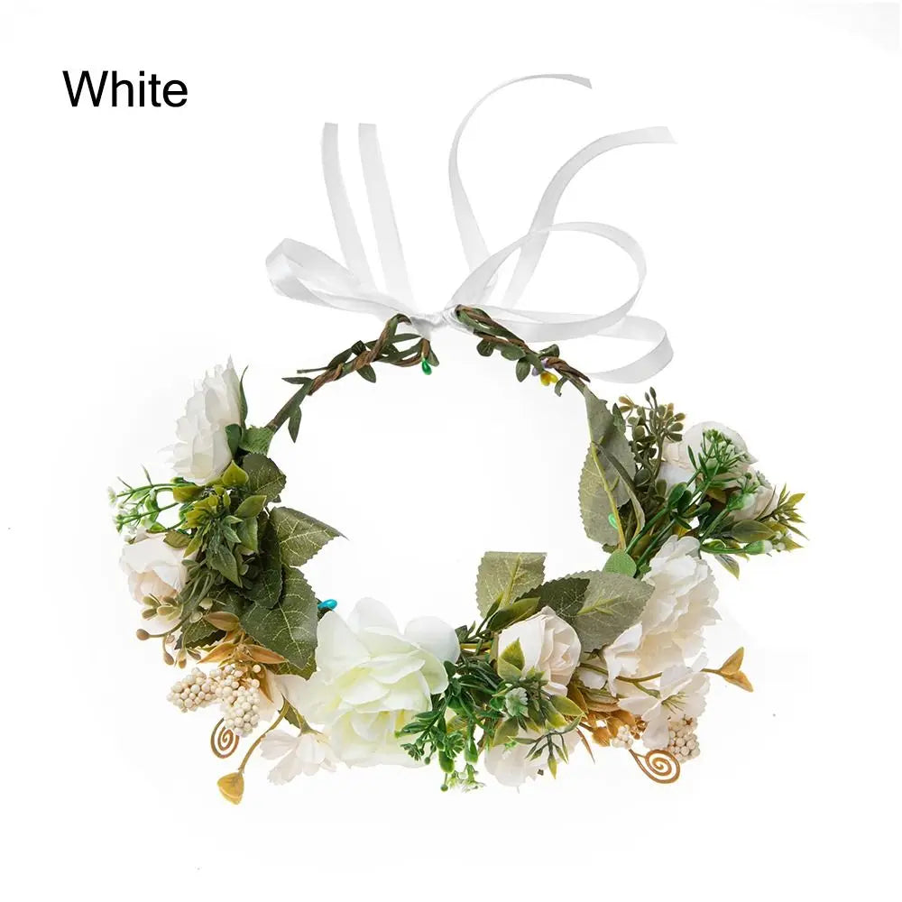 White bohemian flower headband featuring greenery and white flowers with a sheer ribbon bow.