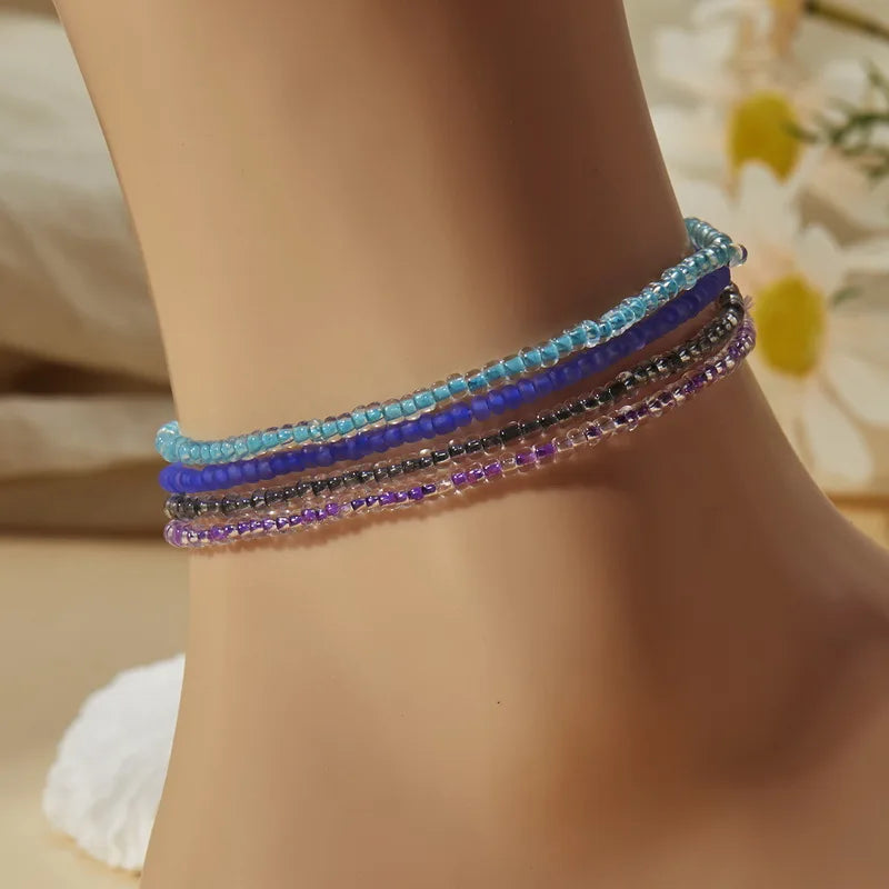 A bracelet featuring multiple strands of luminous glow-in-the-dark beads in shades of blue and purple on a wrist.