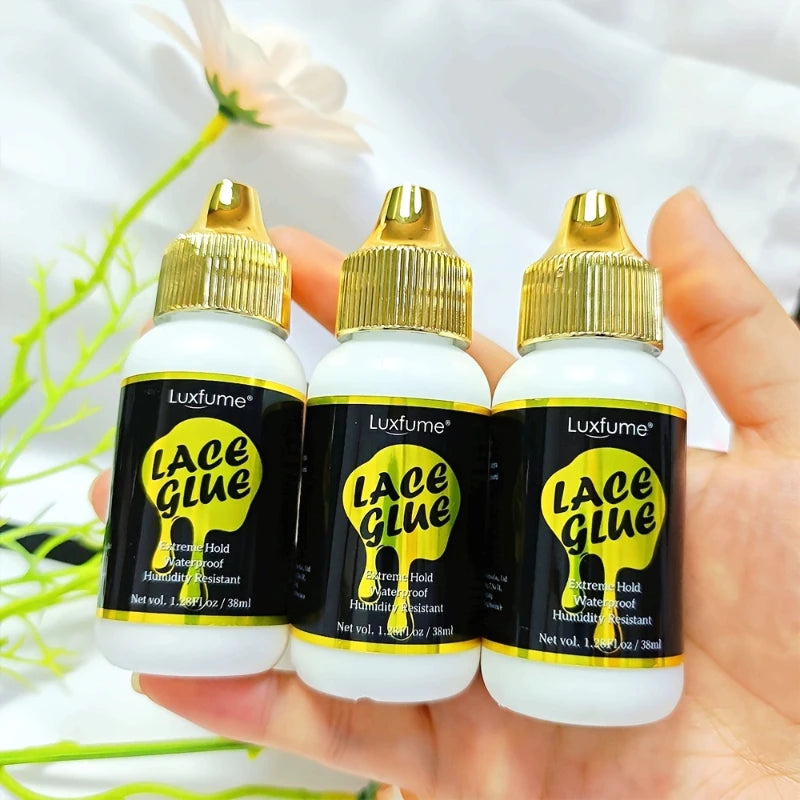 Drei Glasflaschen Luxfume Lace Glue Spray in einer Hand vor weißem Hintergrund